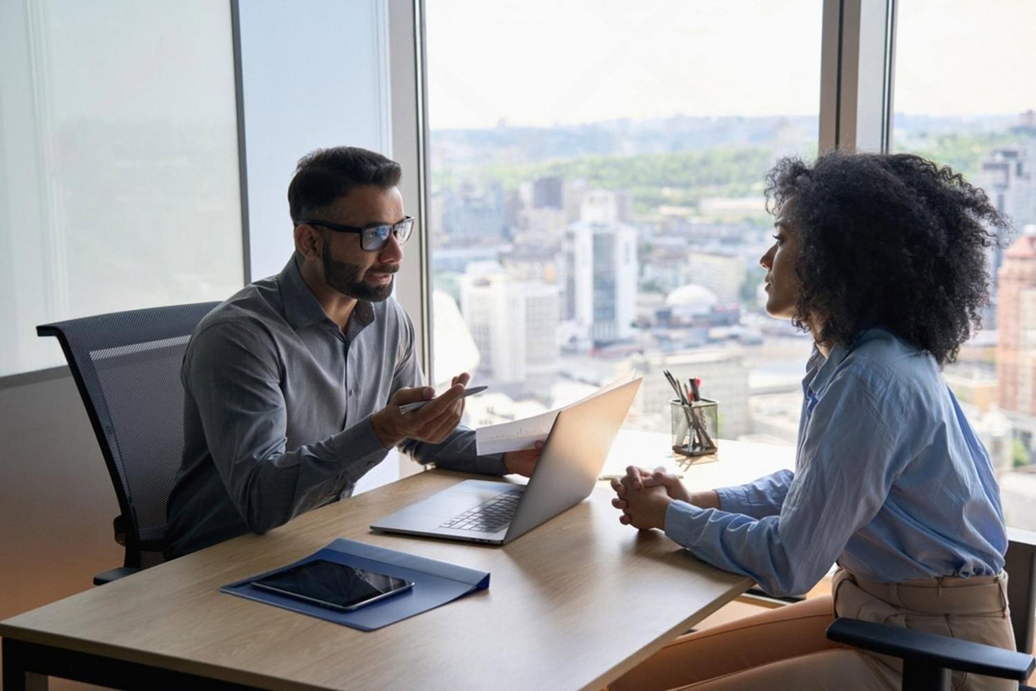 Hiring manager interviewing a female candidate in a Dubai office with city skyline behind them